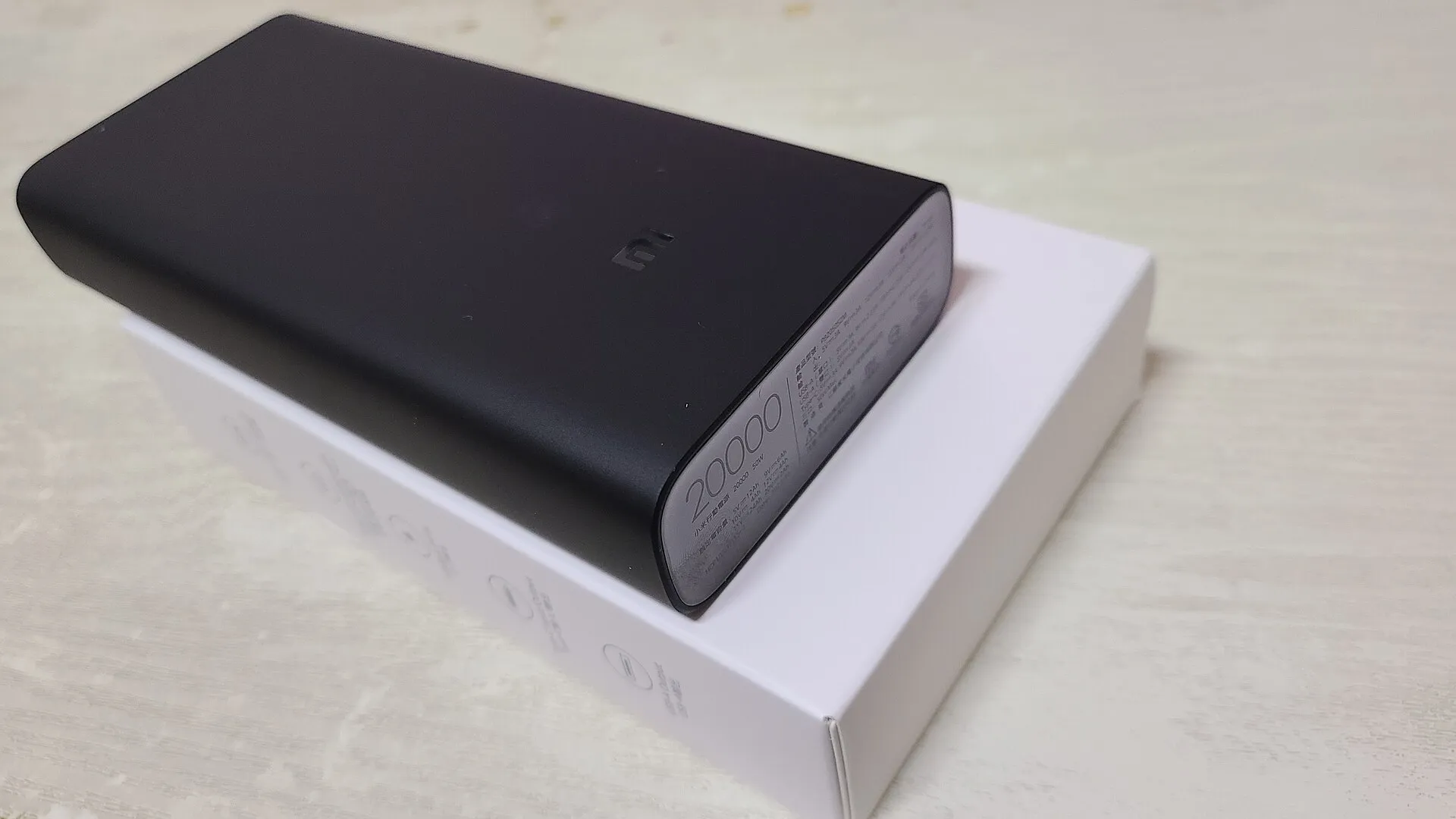 Batterie externe noire de 20 000 mAh, de forme allongée, posée sur sa boîte blanche