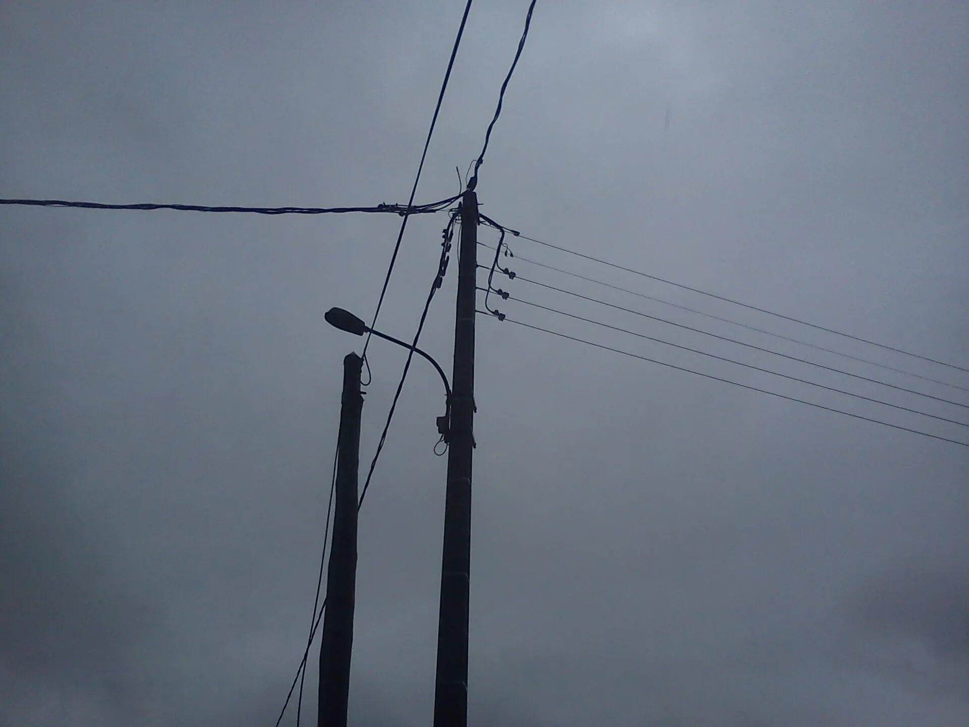 Poteau et fils électriques d'une ligne basse tension dans un ciel gris