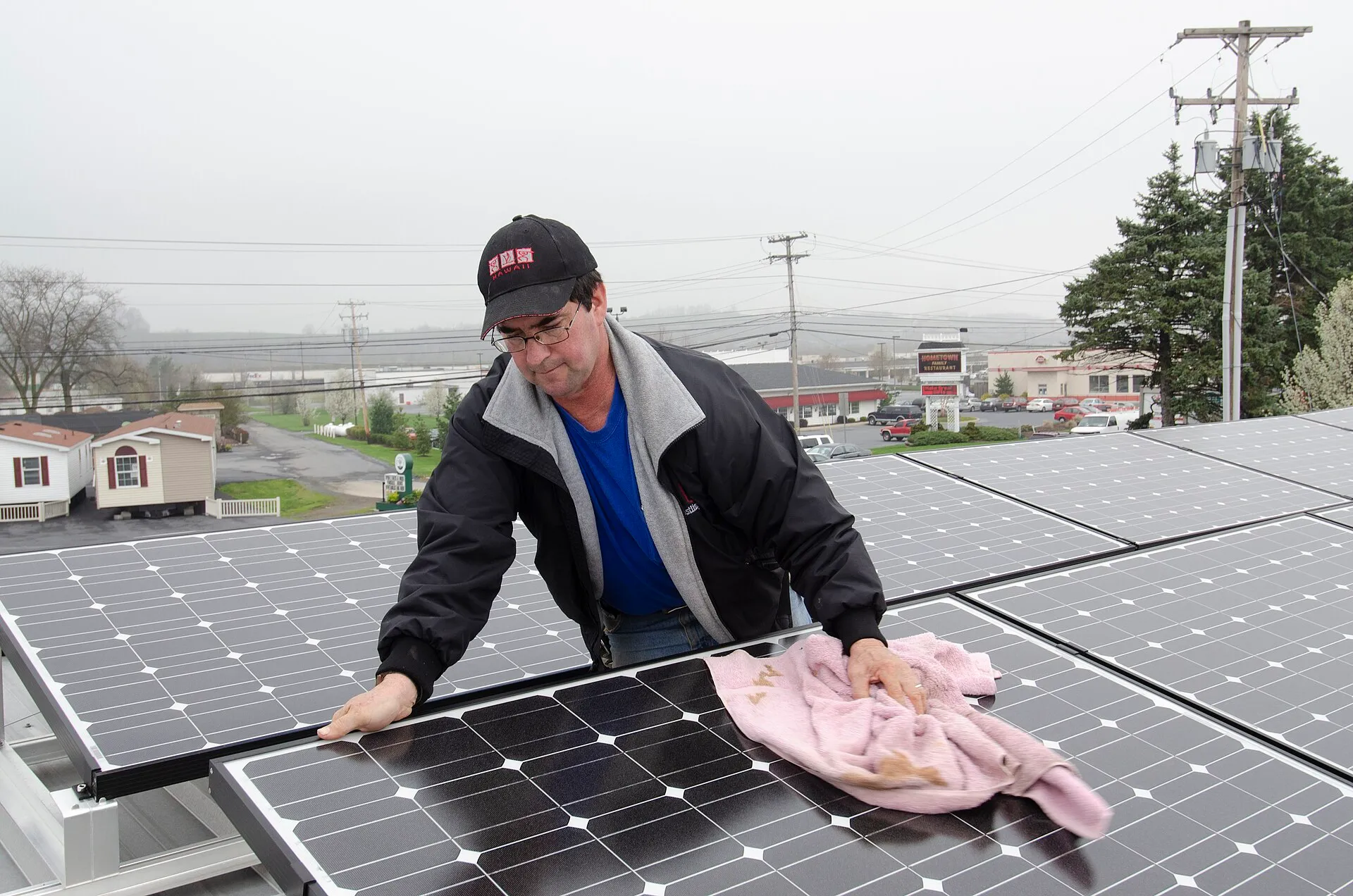 Homme qui nettoie au chiffon un panneau solaire d'une rangée de panneaux