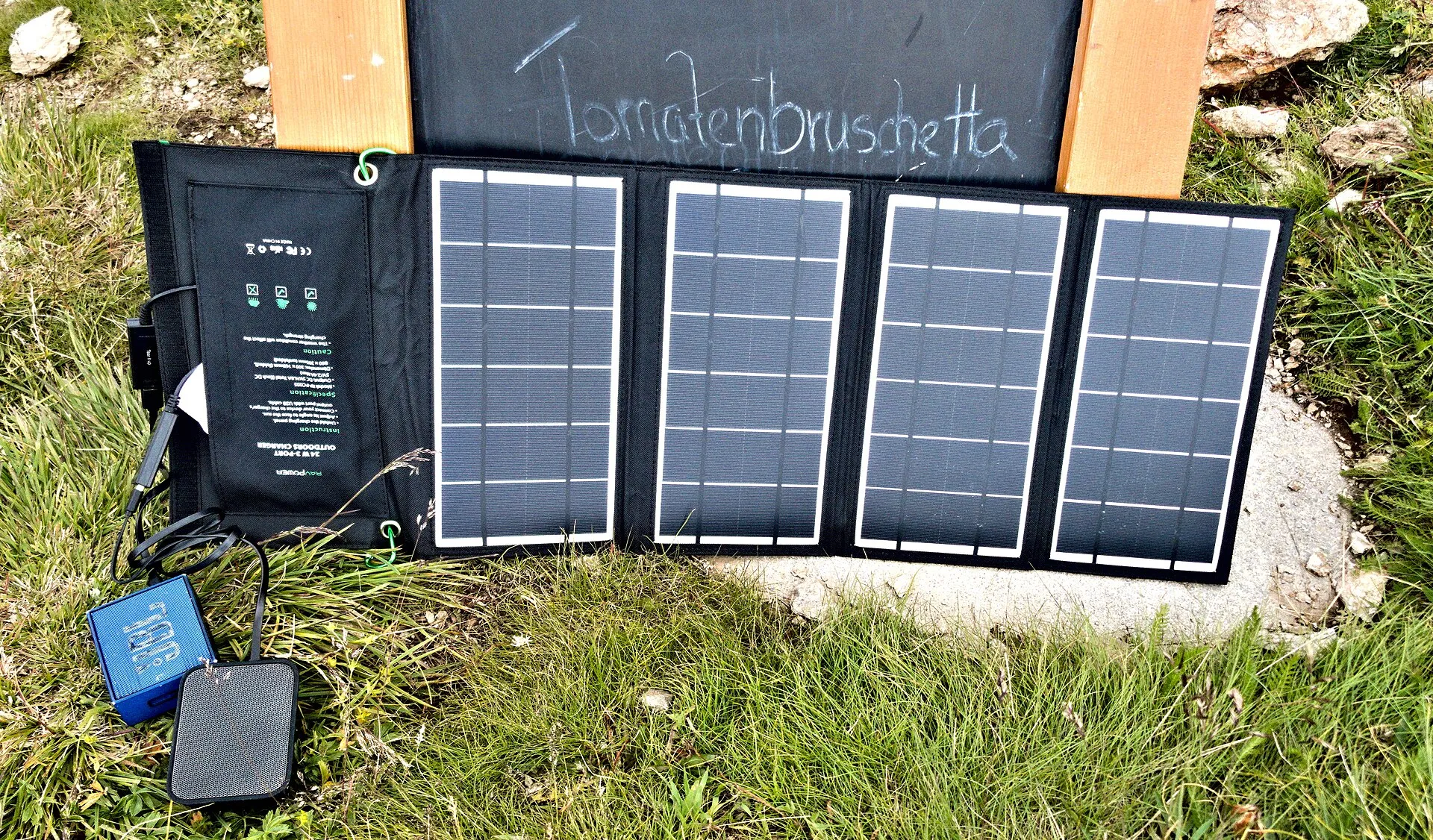 Petit panneau solaire pliable à quatre cellules déplié sur l'herbe, relié à une batterie externe