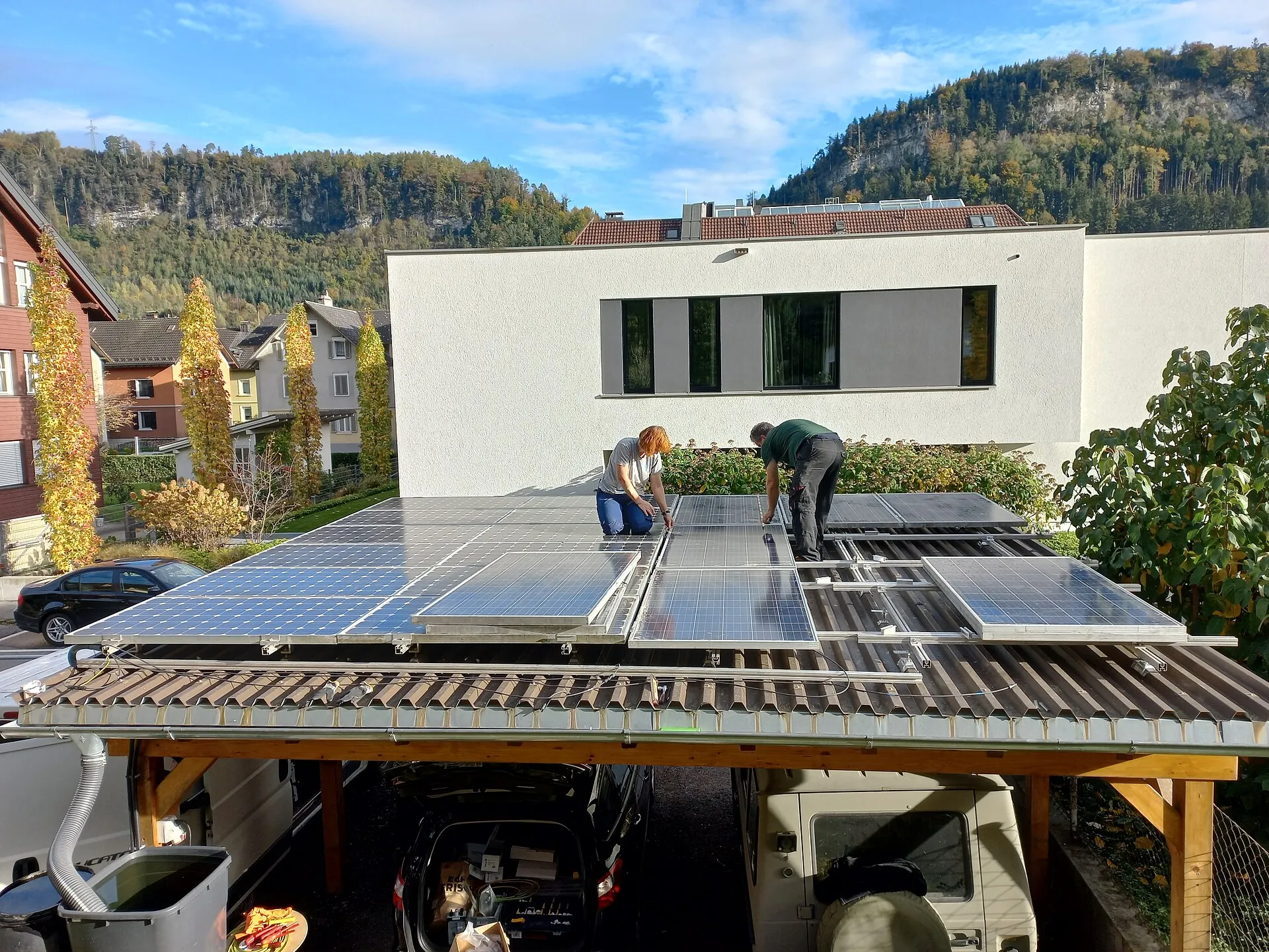Deux installateurs fixent des panneaux solaires sur les rails d'un carport en bois