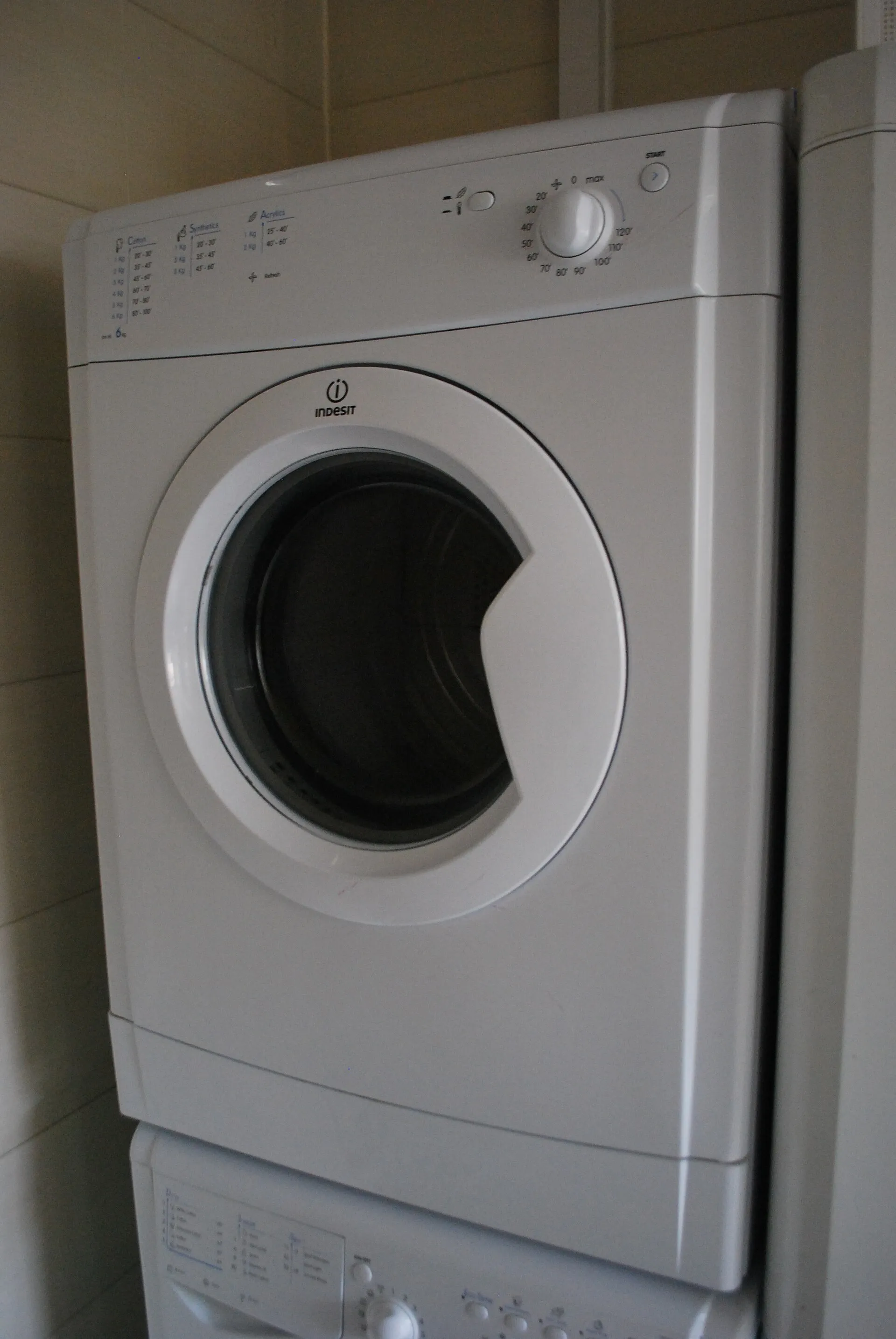 Sèche-linge à hublot posé sur un lave-linge dans une buanderie